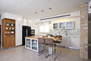 מטבח כפרי עם מספר רב של חללי אחסון למראה נקי ומסודר. קרדיט צילום: רן ארדה.